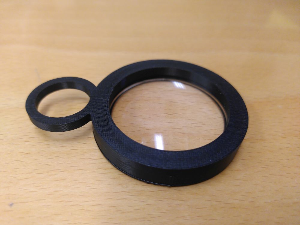 Lens / Lupe Lupe mit schwarzem Gehäuse auf Holzuntergrund