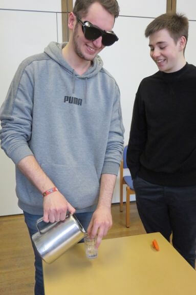Spaß beim Wassereinschenken mit Simulationsbrille. Jugendlicher mit Simulationsbrille schenkt Wasser in ein Glas.
