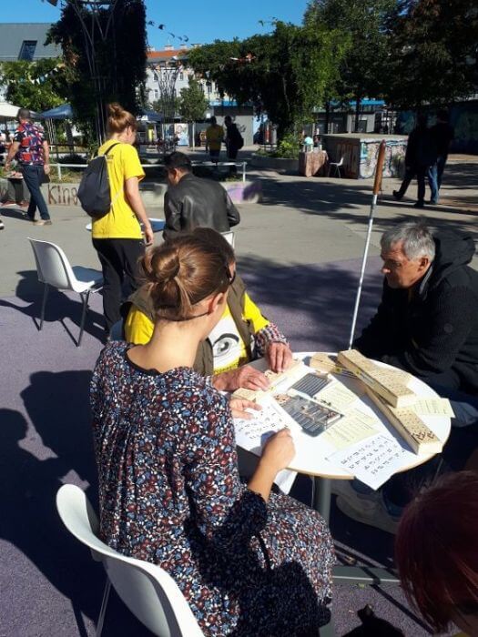 Neugier und Freude am Ausprobieren beim Visioneers Festival 3 Personen sitzen bei einem Tisch und testen die Brailleschrift