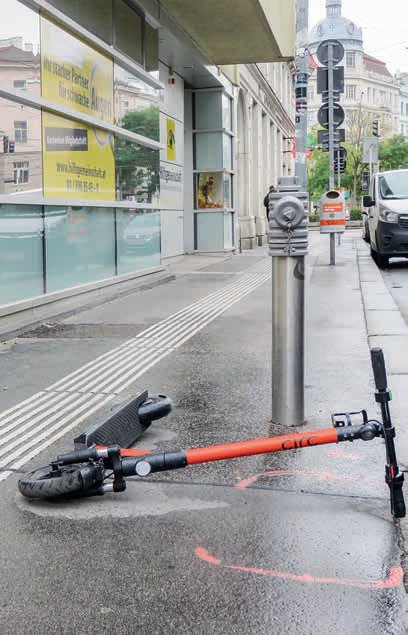 E-Scooter als Hindernisse am Gehsteig Ein oranger E-Scooter liegt auf einem Gehsteig direkt neben dem Blindenleitsystem.