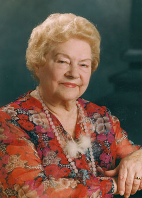 Hildegard Emmer Eine ältere Dame in bunter Bluse blickt lächelnd in die Kamera