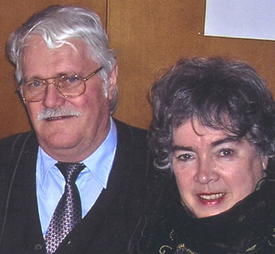 Monika und Herbert Neumann Ein älteres Ehepaar steht lächelnd, eng nebeneinander und blickt in die Kamera.