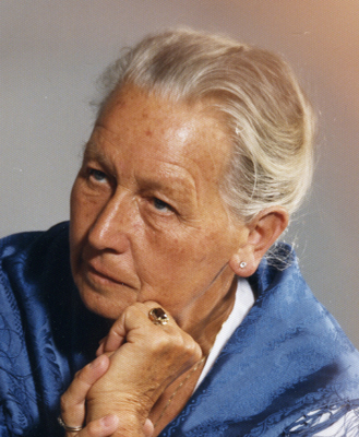 Maria Kienesberger Foto einer älteren Dame mit blauem Tuch um die Schultern, sie blickt nicht in die Kamera und hat ihren Kopf auf die Hände gestützt