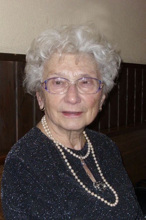 Maria Peter Eine ältere Dame mit Dauerwelle, großer Brille und mehrerer Ketten um den Hals blickt leicht lächelnd in die Kamera