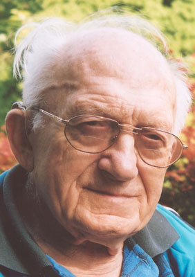 Otto Salzborn Ein älterer Herr mit Brille lächelt freundlich in die Kamera, hinter ihm grüne Bäume