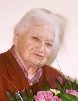 Stefanie Fleischmann Eine ältere Dame lächelt in die Kamera, vor ihr ist ein großer Blumenstraß zu sehen.