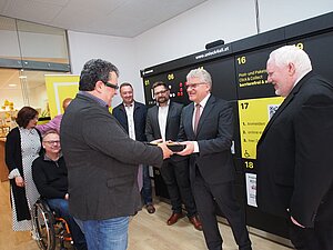 Mann übergibt Torte an anderen Herren vor Paketbox