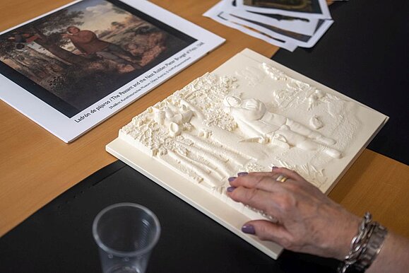 Ein tastbares Relief macht bildende Kunst für Menschen mit Sehbehinderung begreifbar. Foto: Kunsthistorisches Museum. Hand einer älteren Person berührt weißes Tastrelief eines Gemäldes.