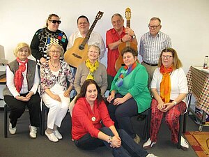 Zehn Personen stehen und sitzen in drei Reihen vor der Kamera