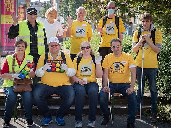Mitglieder der Hilfsgemeinschaft bei einem Boggia-Ausflug: Neun Menschen winken fröhlich vom Gruppenfoto