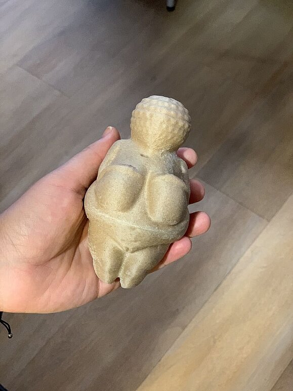 3D-Drucker-Hilfsmittel-Event_Venus_von_Willendorf_taktil.jpg Hand hält Figur der Venus von Willendorf in der Hand