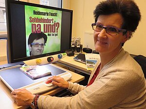 Frau Feucht zeigt auf dem Bildschirmlesegerät stolz ihr eigenes Buch Frau Feucht sitzt vor dem Bildschirmlesegerät, auf dem ihr Buch zu sehen ist