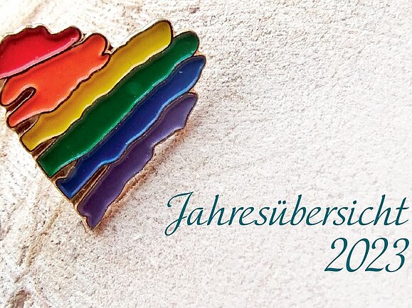 Die Hilfsgemeinschaft wünscht alles Gute für 2023! Ein Regenbogen-Herz auf hellem Hintergrund, daneben steht Jahresübersicht 2023