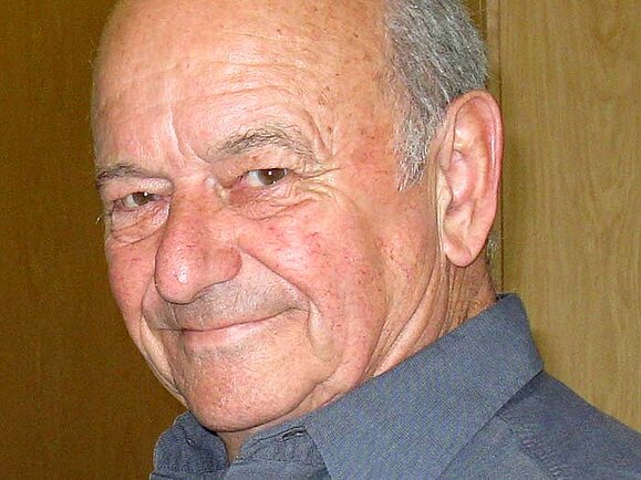 Othmar Fahrner Portraitfoto eines älteren herren mit kurzen grauen Haaren, der ein graues hemd trägt. Er lächelt verschmitzt in die Kamera.