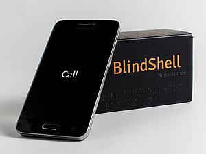 Ein Smartphone lehnt an einer Box mit der Aufschrift BlindShell