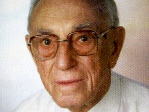 Heinrich Roisl Foto eines älteren Herren mit Brille und weißem Hemd, der milde in die Kamera lächelt