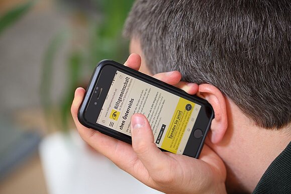reiter_beratung_Barrierefreiheit__c_Schedl_Hilfsgemeinschaft_A3 Mann hält Smartphone ans Ohr und lässt sich Website vorlesen