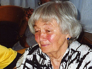 Helene Schütz
Ältere Dame lächelt milde, hält ein Glas Apfelsaft in der Hand.