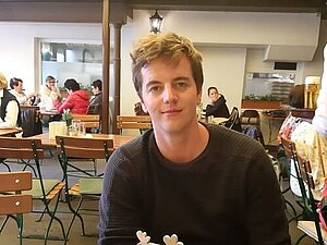 Maximilian Reutterer sitzt in einem Restaurant und lächelt in die Kamera. 