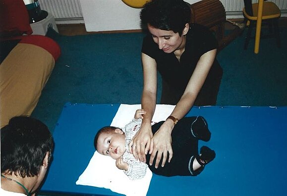 Frau massiert Kleinkind auf blauer Matte den Bauch