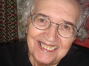 Erika Feyerfeil Eine ältere Dame mit Brille lächelt fröhlich in die Kamera