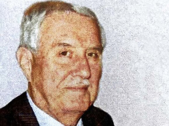 Hans Lichtblau Portrait, älterer Herr mit weißen Haaren und Schnautzbart in Hemd und Anzug vor einem grauen Hintergrund.