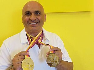 Bil Marinkovic mit zwei Silbermedaillen der Para-EM Berlin 2018 neben dem Logo der Hilfsgemeinschaft