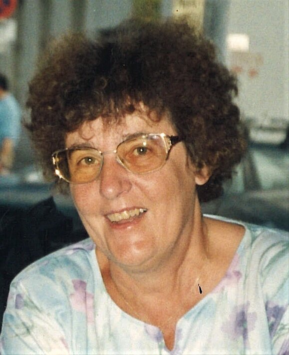 Szlovak Renate Portrait einer Dame mittleren Alters mit braunen Locken und Brille, freundlich lachend.