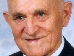 Heinrich Wiedersheim Portrait eines älteren Herren mit Anzug und Krawatte der milde lächelnd an der Kamera vorbeiblickt