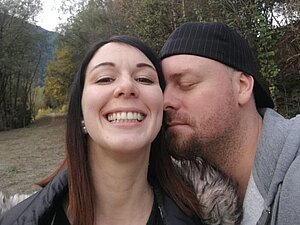 Als Sandro plötzlich eine Seheinschränkung hatte, war die Beratung der Hilfsgemeinschaft eine große Stütze, um die Anträge zu bewältigen. Foto: privat. Junges Paar in Selfiemodus, Mann hat die Augen geschlossen und Nase auf der Wande der grinsenden Frau