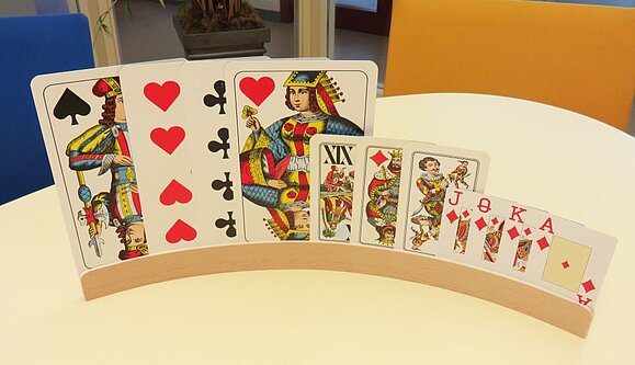 Spielkarten gibt es in unterschiedlichen Größen. Auf einem Spielekartenhalter sind 3 große, 3 mittlere und 4 kleine Karten eingesteckt.
