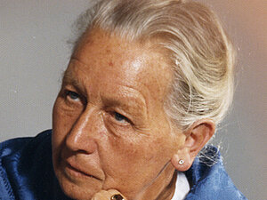 Maria Kienesberger Foto einer älteren Dame mit blauem Tuch um die Schultern, sie blickt nicht in die Kamera und hat ihren Kopf auf die Hände gestützt