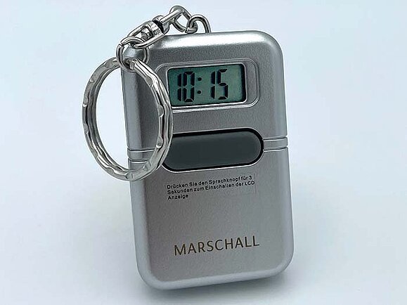 Ein silberner Schlüsselanhänger mit Zeitanzeige und einem großen Knopf.