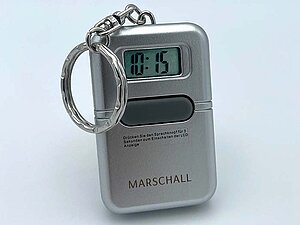 Sprechender Anhänger für den Schlüsselbund. Ein silberner Schlüsselanhänger mit Zeitanzeige und einem großen Knopf.