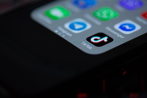 Wie barrierefrei ist die Social Media Plattform TikTok? Foto: Unsplash. unteres rechtes Eck von iPhone mit Menüansicht: TikTok App im Fokus