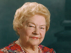 Hildegard Emmer Eine ältere Dame in bunter Bluse blickt lächelnd in die Kamera