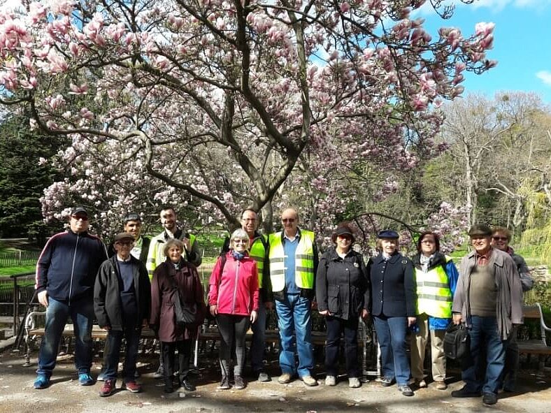 Eine Gruppe von 13 Personen steht im Park vor einem blühendem Baum.