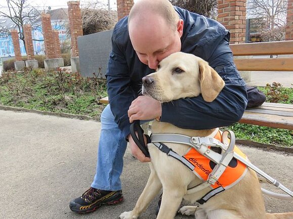 Zwischen Alexander S. und seinem Blindenführhund Flint war es Liebe auf den ersten Blick. Alexander S. kuschelt auf einer Parkbank mit seinem Blindenführhund Flint