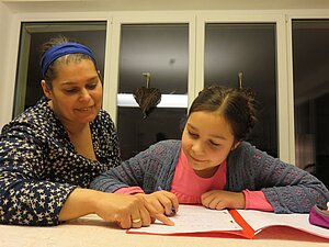 Julia macht gemeinsam mit ihrer Mama die Hausaufgaben. Ein sehbehindertes Mädchen macht mit ihrer Mama Hausaufgaben.