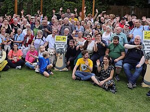 Gute Laune bei der Jubiläumsfeier Ein Gruppenfoto von vielen Menschen mit dem Maskottchen AUGust
