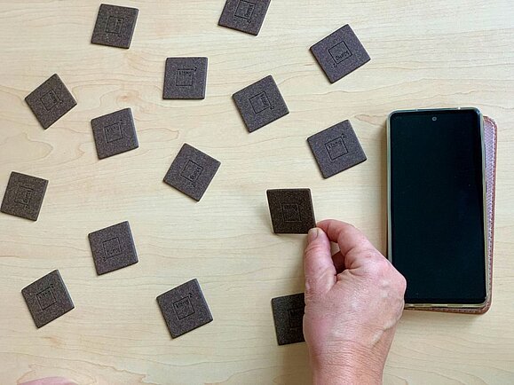 Hand hebt dunkelbraune Memory-Karte, rechts Handy