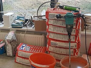 So sieht es auf unserer Baustelle in Floridsdorf aus. Vor einem Fenster sieht man Bau-Utensilien und Werkzeug liegen.