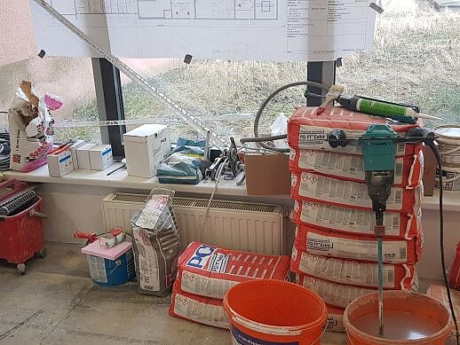 So sieht es auf unserer Baustelle in Floridsdorf aus. Vor einem Fenster sieht man Bau-Utensilien und Werkzeug liegen.