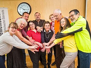 Gemeinsam mehr bewegen, das ist freiwilliges Engagement bei der Hilfsgemeinschaft, Copyright: Franz Pfluegl Mehrere Menschen stehen in einem Halbkreis und strecken die Hände alle in die Mitte.