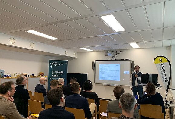 Präsentationsteilnehmer im Raum blicken auf Leinwand