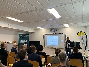 Präsentationsteilnehmer im Raum blicken auf Leinwand