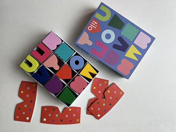 Das Spiel ist für viele Zielgruppen geeignet. Tastspiel tilo Verpackung von oben geöffnet, man sieht alle bunten Formen in der Packung eingeschlichtet