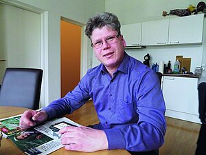 Peter G. sitzt an einem Tisch mit einer elektronischen Lupe. Peter G. sitzt an einem Tisch mit einer elektronischen Lupe.