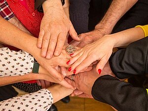 Ehrenamtliche legen im Kreis die Hände zusammen, Copyright: F. Pfluegl.