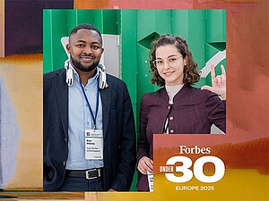 Links im Bild ist Brian Mwenda zu sehen, der ein Sixth Sense-Gerät auf seinen Schultern trägt, rechts steht Laura Wissiak, die mit ihrer linken Hand das ILY-Zeichen zeigt. Das Bild ist von einem orangefarbenen Rahmen umgeben, in einer Ecke befindet sich das Logo von Forbes Under 30 Europe 2025.